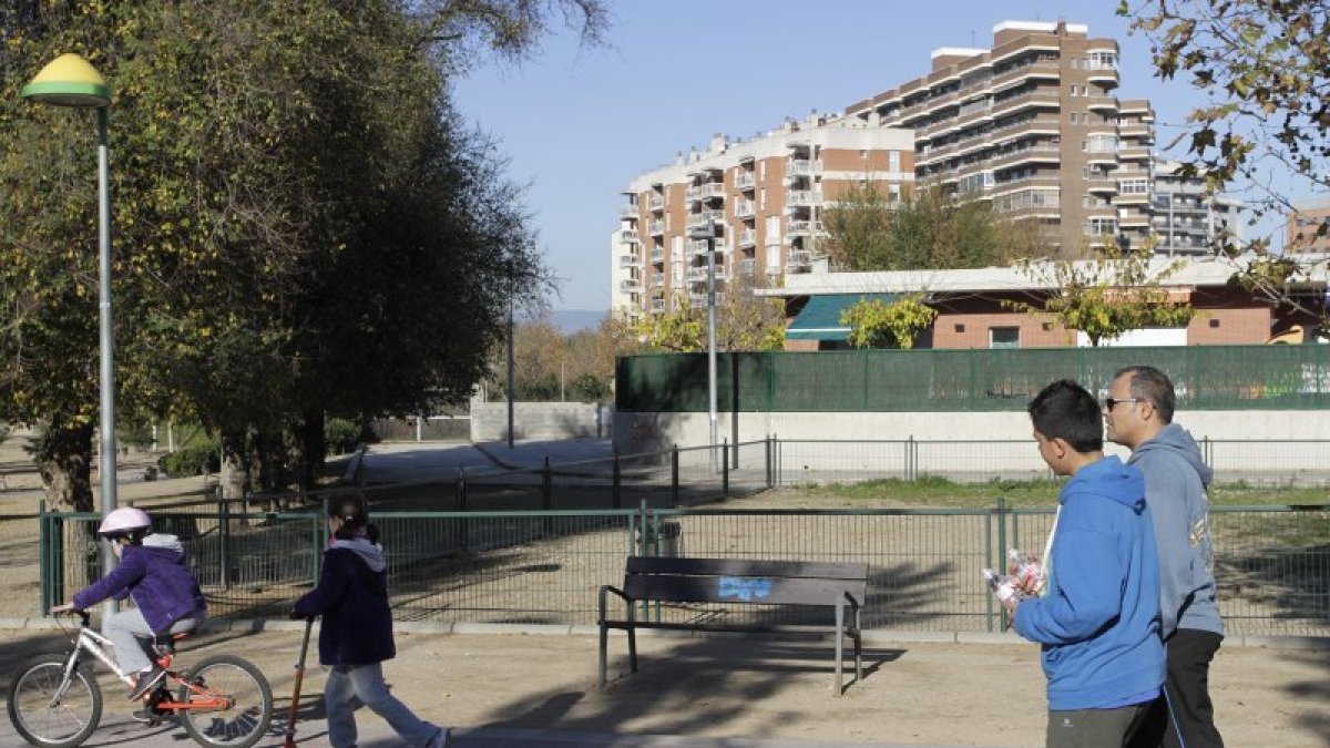 Dos niños pasan ante el pipicán del Parc del Francolí, cuya ubicación ha generado polémica al estar colocado ante el patio de una guardería, con lo que el olor llega a los pequeños.