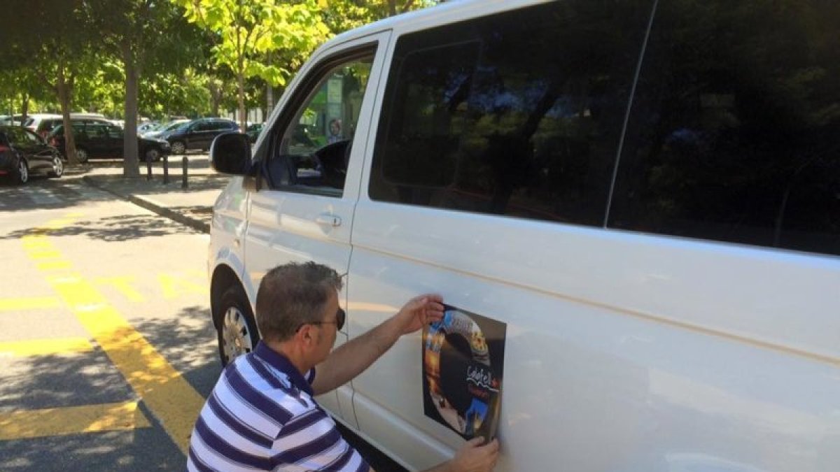Un taxista coloca el logo que identificará a los profesionales con licencia.