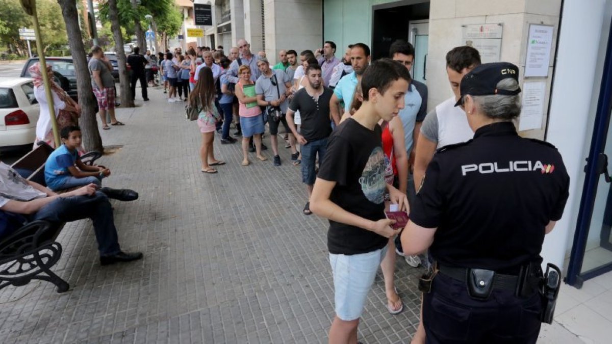 En la imagen, los dos primeros ciudadanos de la cola reciben el tiquet para poder renovar los documentos.