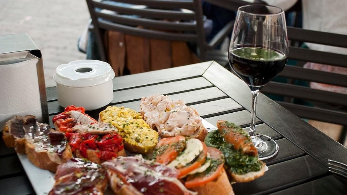 Imagen de unas tapas y un vino tinto.