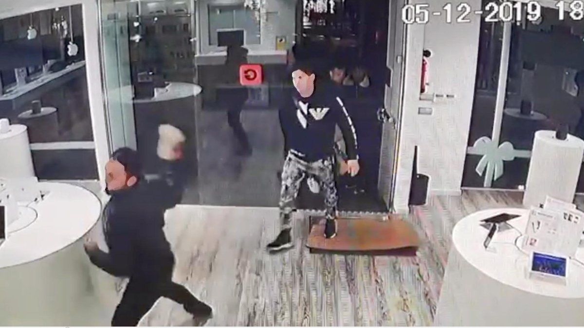 Un ladrón tira una piedra contra un cristal de una estantería.