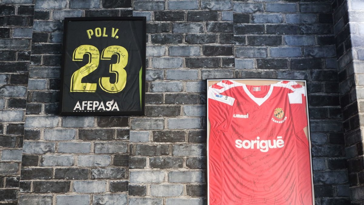 Las camisetas de Pol Valentín y otra con las firmas de la plantilla entera cuelgan en la peluquería.
