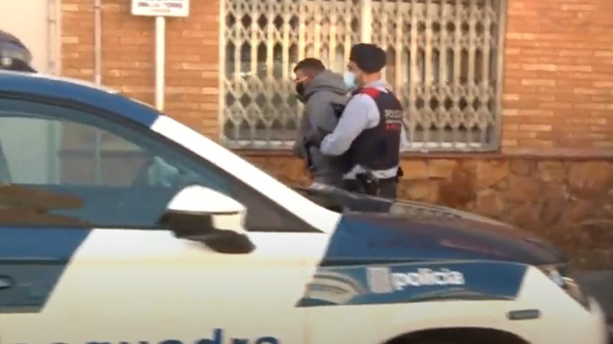 Momento en que un mosso se lleva al primero de los tres detenidos de la operación.