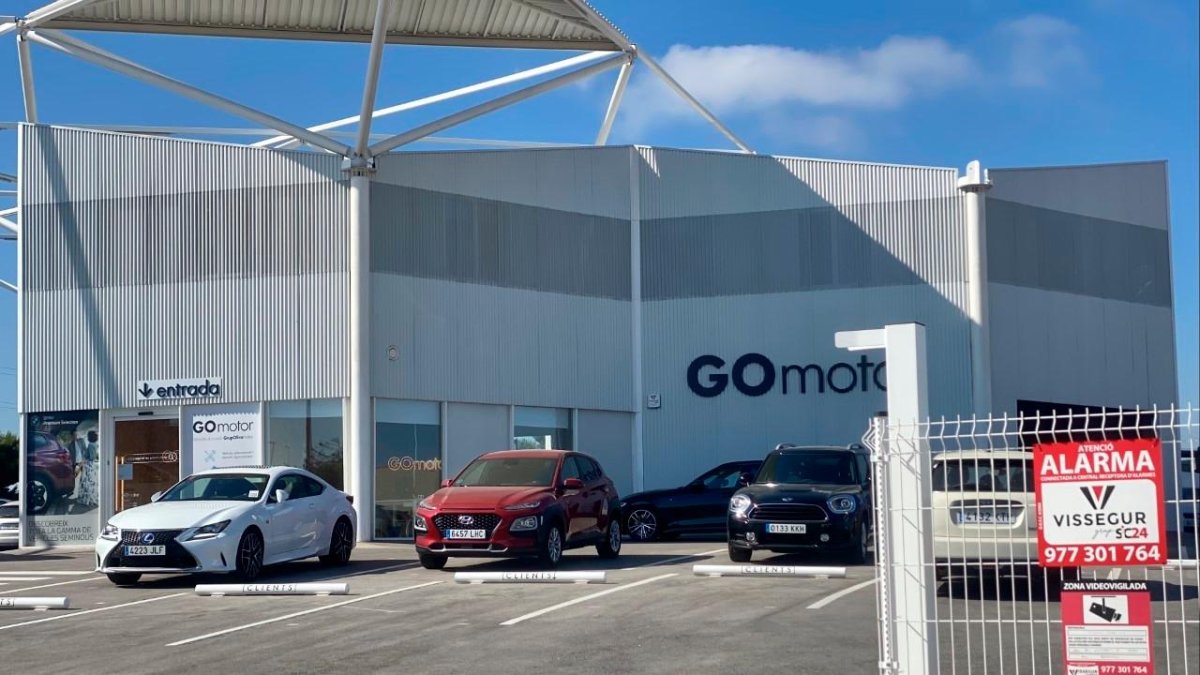 Los vehículos están estacionados al aire libre, pero dentro del recinto del concesionario.