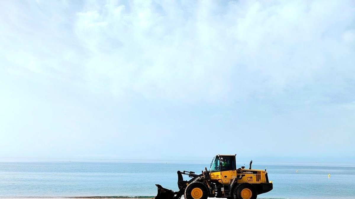 Una de las excavadoras que ayer por la mañana estaba repartiendo la arena que procede de la playa del Vinyet.