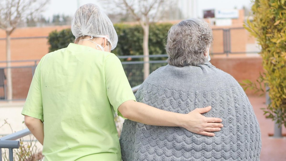 Imagen de una cuidadora atendiendo a una persona mayor.