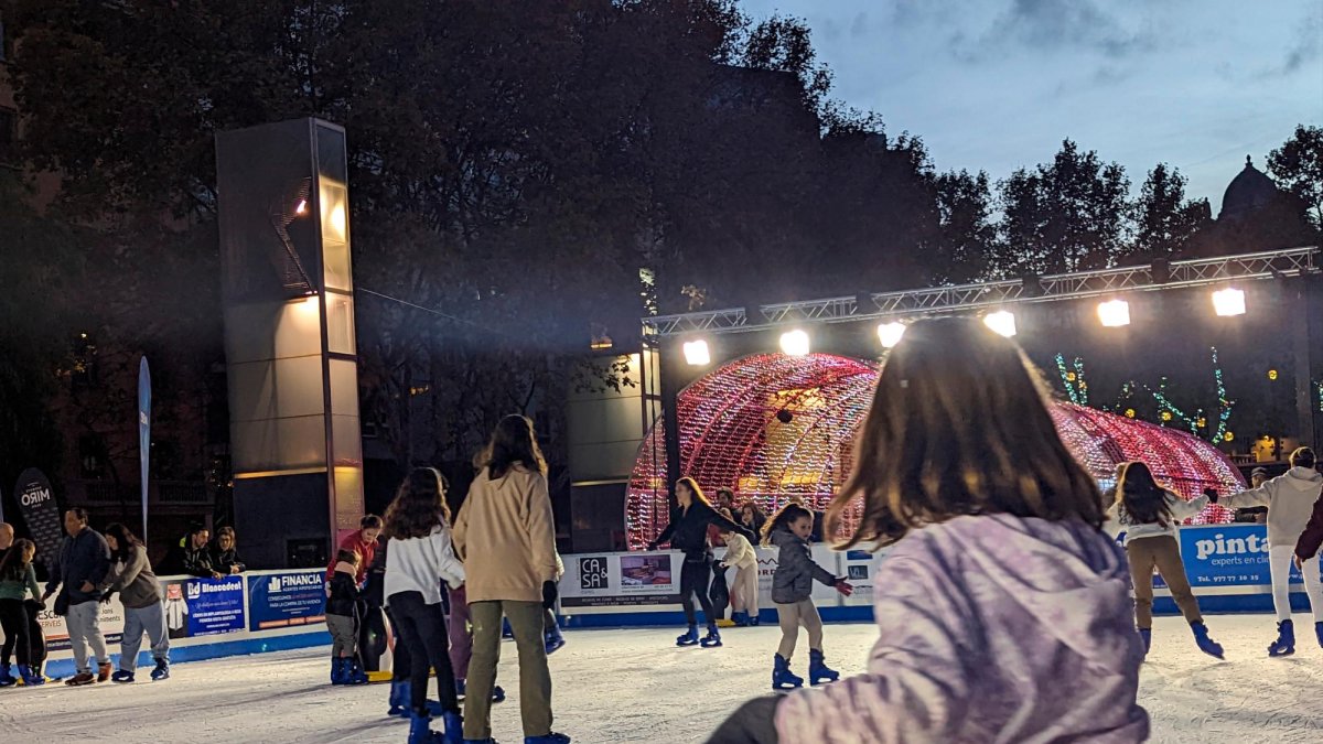 Niños y adultos disfrutan de la pista de patinaje sobre hielo.