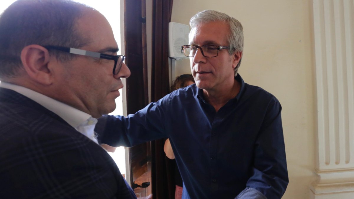 El concejal Josep Maria Prats abrazándose con el alcalde tras su comparecencia de prensa.