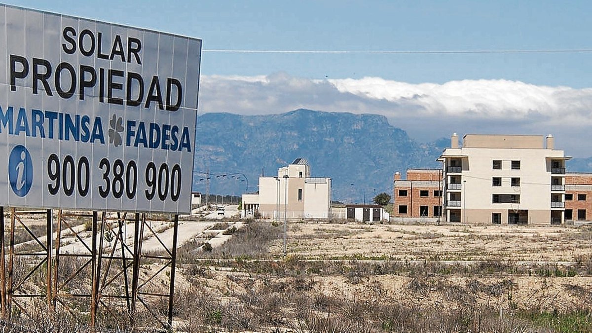 El cartel de Martinsa Fadesa, que quebró hace diez años. Al fondo, la urbanización fantasma del Mirador del Ebro, en L’Aldea.
