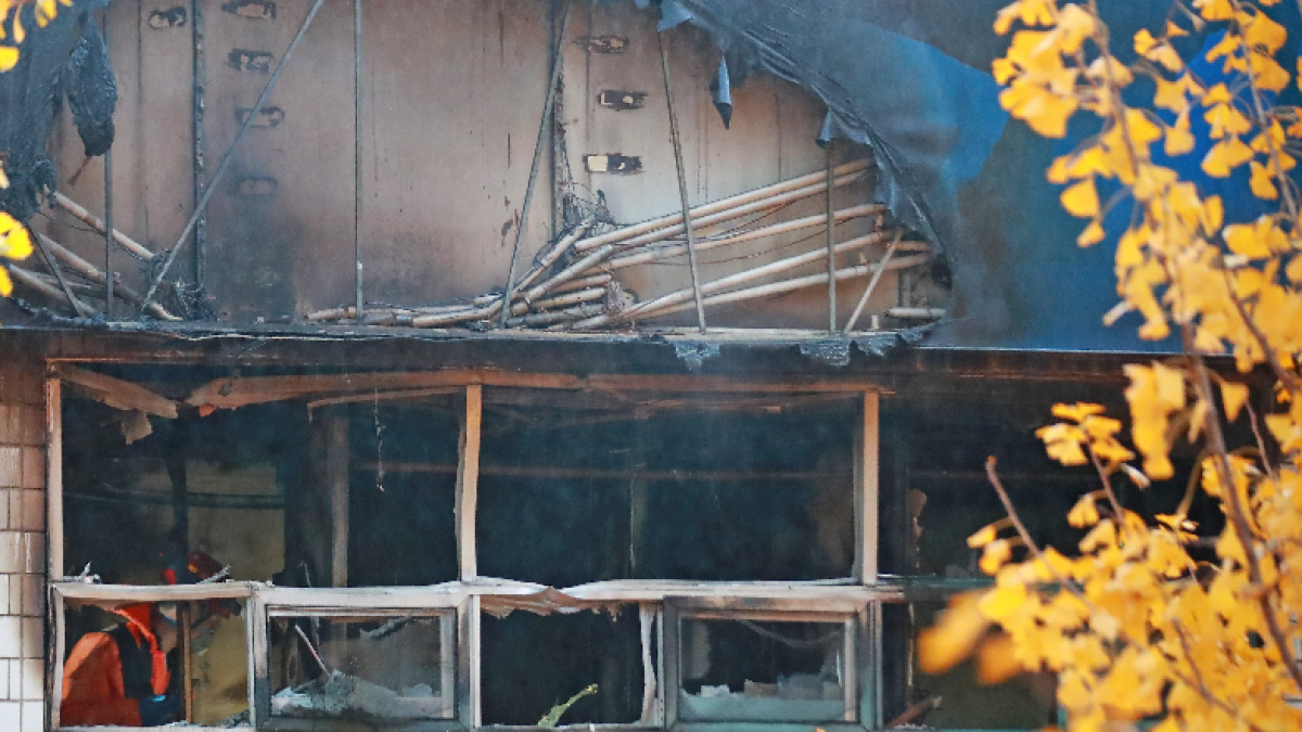 Un bombero camina a través de una casa de huéspedes destruida por un incendio.