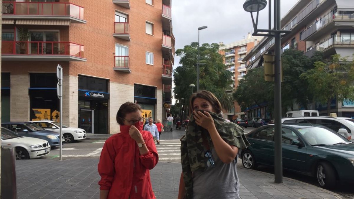 Dos mujeres, esta mañana caminando con precaución en Tarragona.