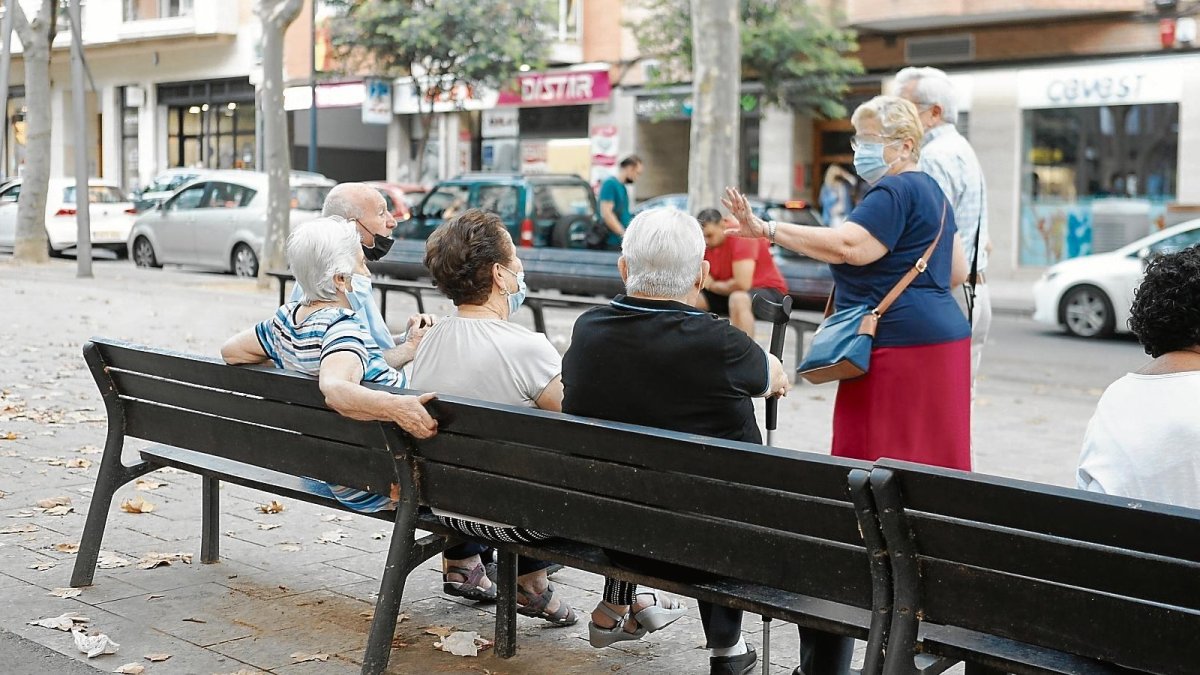 Varias personas mayores charlando en un banco del paseo Prim de Reus.