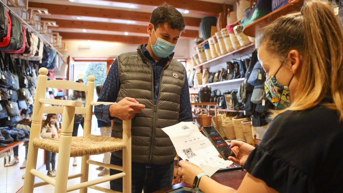 Un cliente usando un bono en una de las tiendas adheridas. Todas ellas tienen un distintivo en el escaparate.