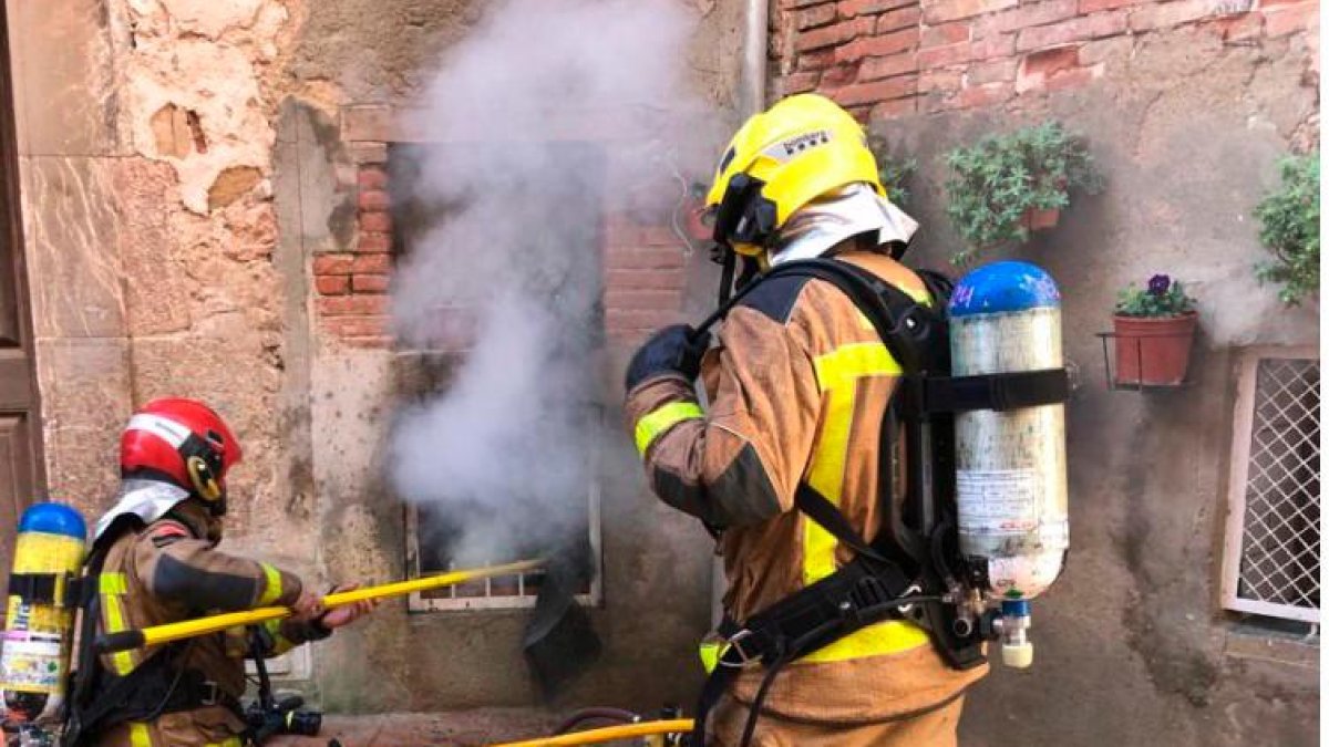 Los bomberos durante los trabajos de extinción por una ventana.