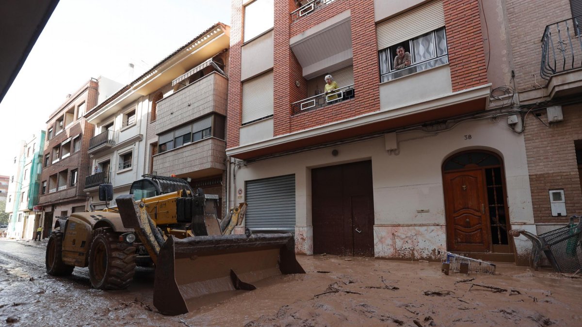Una máquina escavadora retira el lodo acumulado en las calles tras las intensas lluvias caídas por la fuerte dana, este jueves en Catarroja.