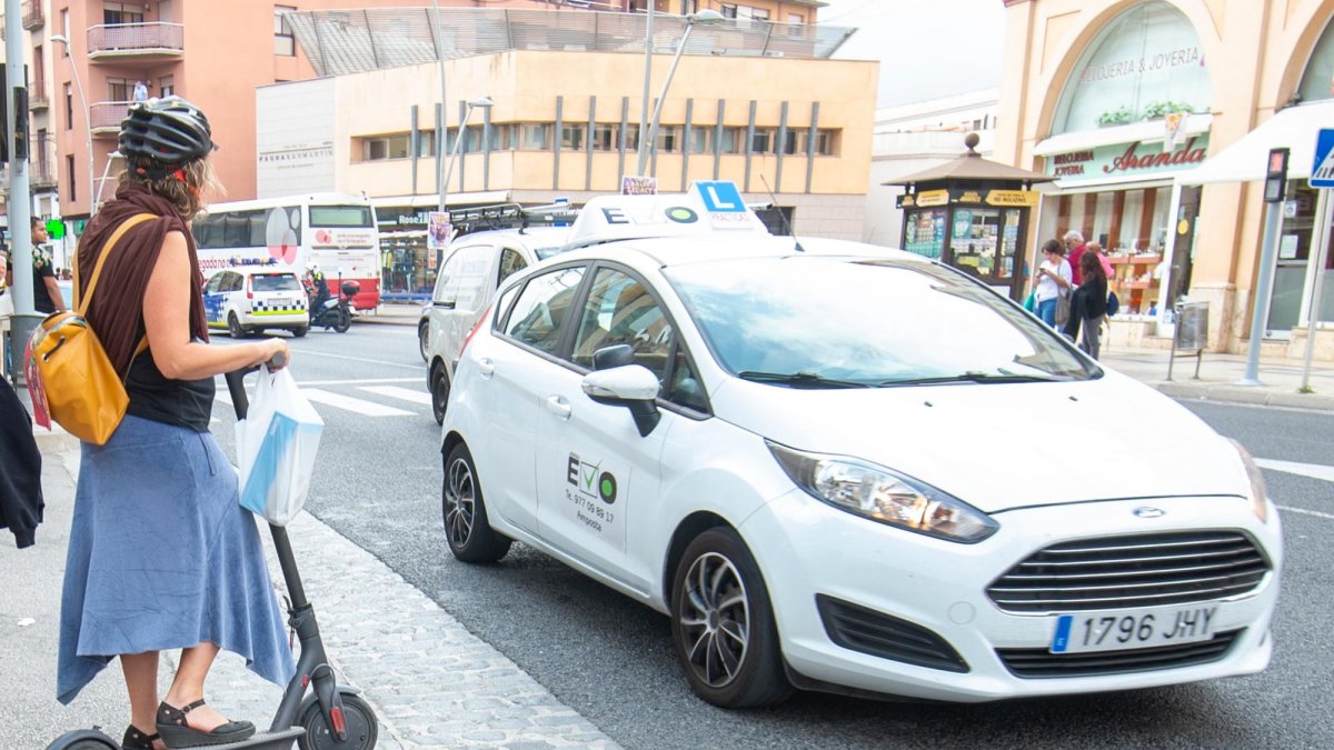 Una dona descendint de la vorera per poder circular en patinet, al centre de Tortosa.