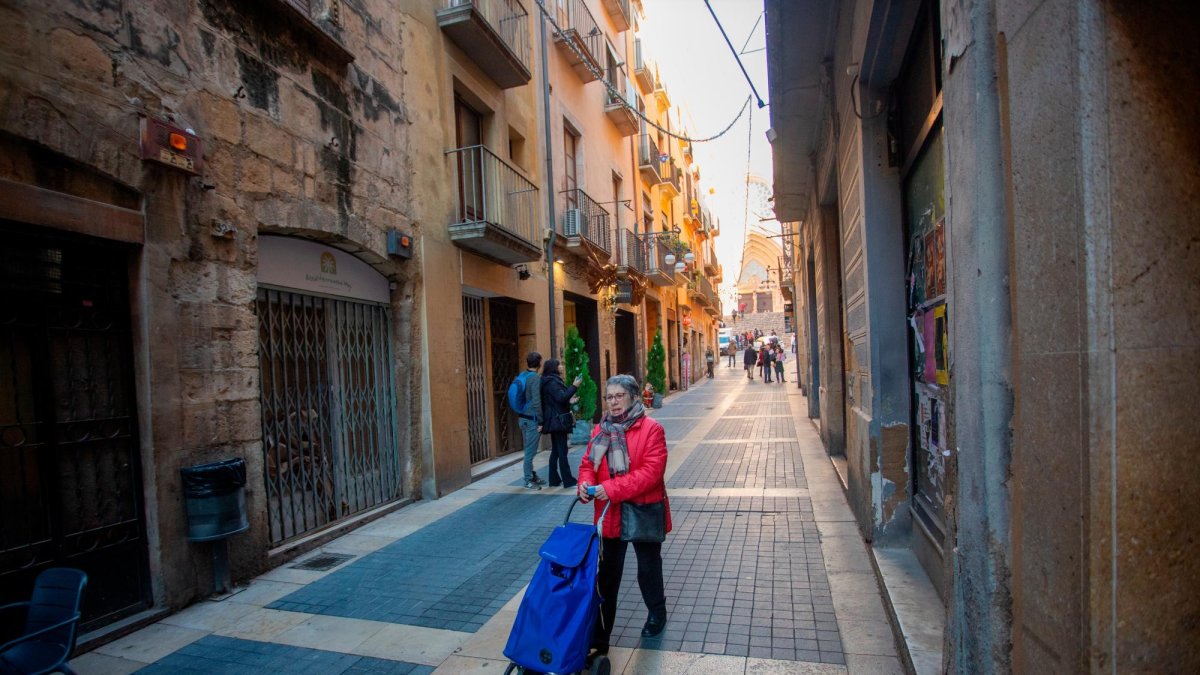 Una mujer empuja un carro por el Carrer Major. La proporción de vecinos mayores ha bajado casi a la mitad en veinte años.