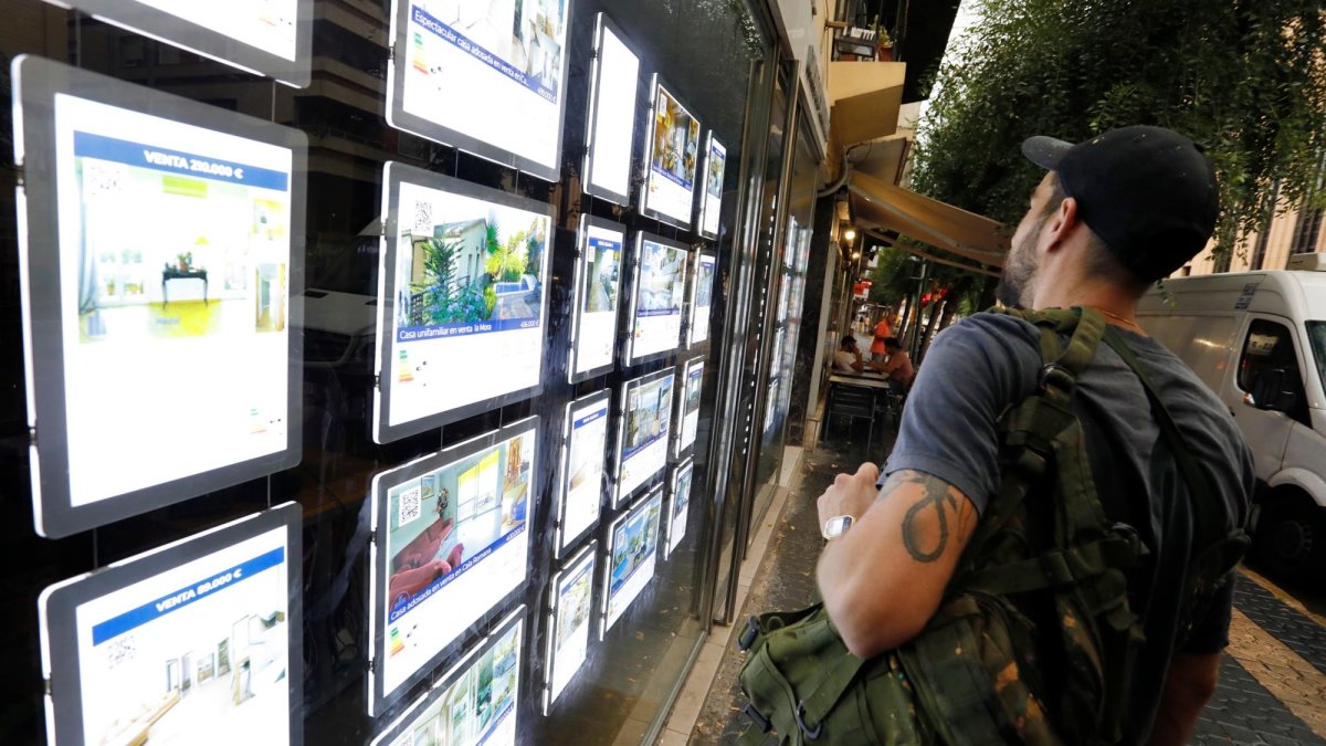 Un joven observa anuncios de inmuebles en el escaparate de una inmobiliaria de la Rambla Vella, en Tarragona.