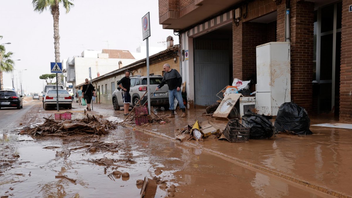 Varias personas limpian el lodo acumulado en sus viviendas a causa de las intensas lluvias por la fuerte dana que afecta especialmente el sur y el este de la península ibérica, este miércoles en Valencia.