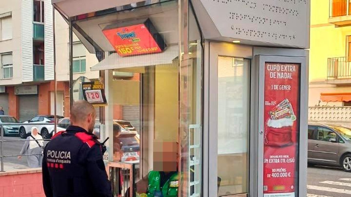 Un agente con la víctima en su quiosco de la calle Riu Fluvià.