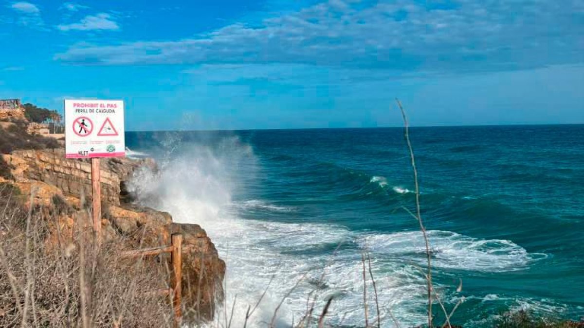 Imagend de la playa del Miracle de Tarragona con un cartel informativo prohibiendo el baño.