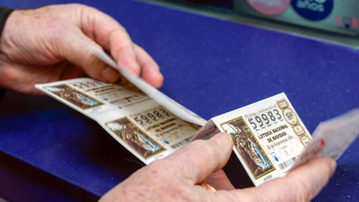 Una persona sostiene algunos décimos de lotería.