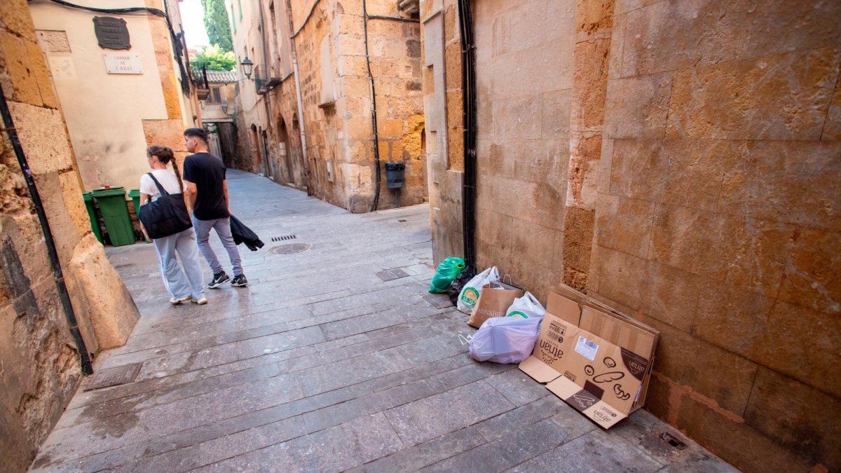 Una calle de la Part Alta con varias bolsas de basura y cartones en el suelo.