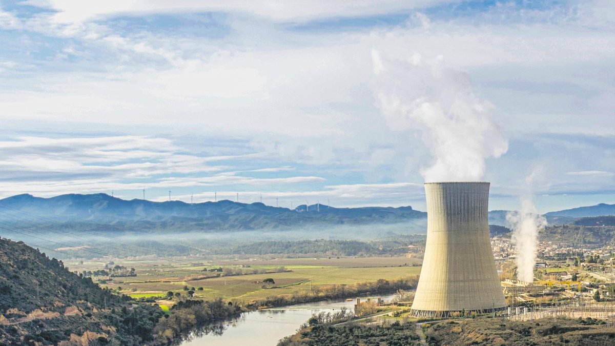 En primer plano, la central nuclear de Ascó, en la Ribera d’Ebre. Al fondo, en el horizonte, algunos molinos eólicos.