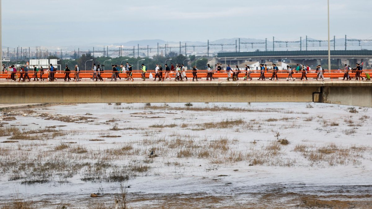Personas cruzando el puente que separa la ciudad de Valencia de los municipios de la comarca vecina de l’Horta Sud afectados por la DANA.