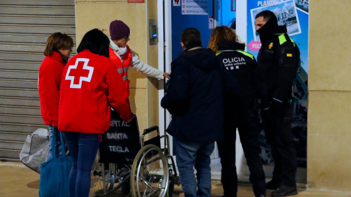 Una patrulla de la Guàrdia Urbana de Tarragona y voluntarios de Creu Roja acompañan hasta el alojamiento donde pasarán en las próximas noches dos personas sin techo, una de las cuales necesita moverse en silla de ruedas.