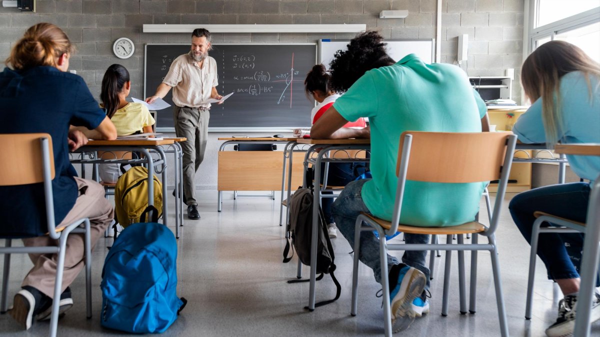 Un profesor reparte material durante una clase.