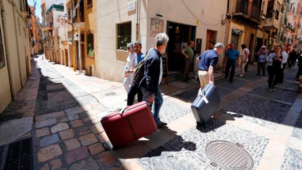 Turistas con maletas caminando por la Part Alta de la ciudad.