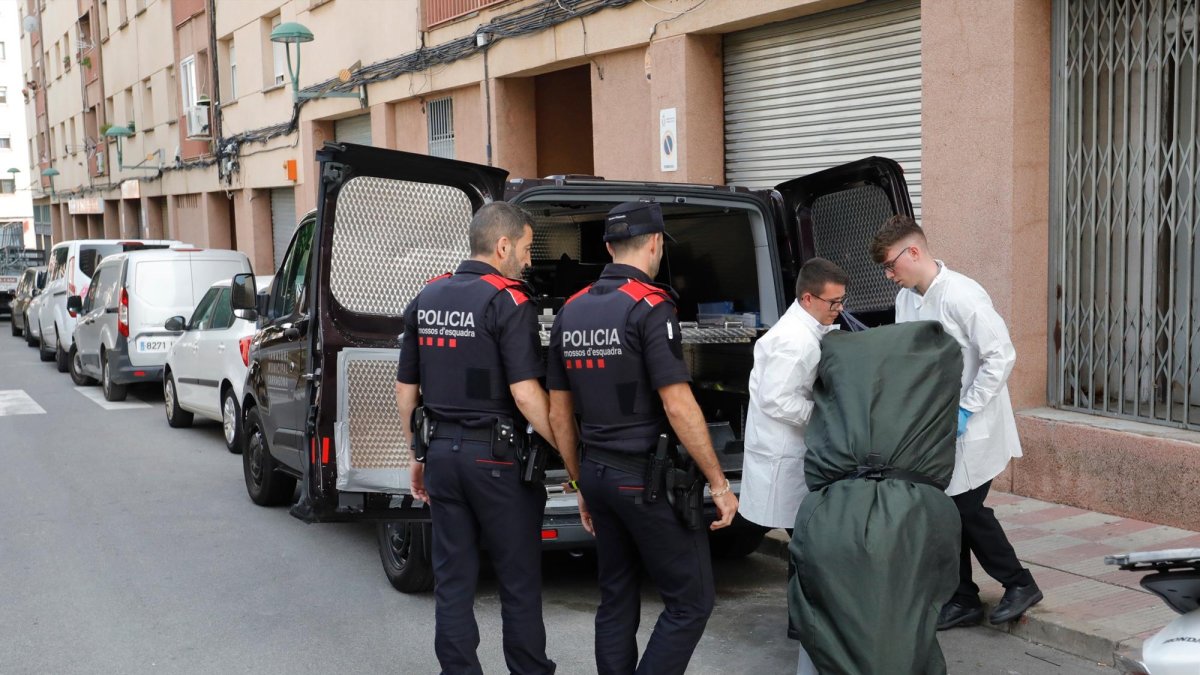 Dos agentes de Mossos y trabajadores de la funeraria con el cadáver de la mujer asesinada.