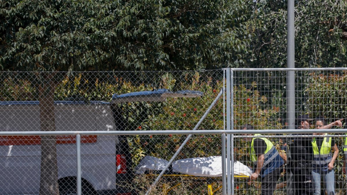 Miembros del retén fúnebre trasladan el cadáver del menor de unos 11 años que desapareció este jueves cuando se bañaba en el río Júcar, a su paso por la localidad valenciana de Alzira, tras haber sido localizado este viernes.
