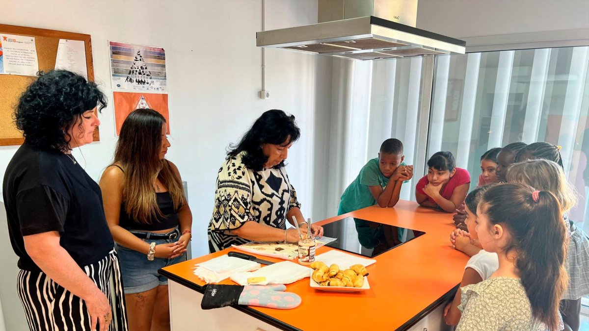 La regidora Anabel Martínez acompanya les monitores i els nens, que aprenen a fer croissants al Centre Cívic Migjorn de Reus.