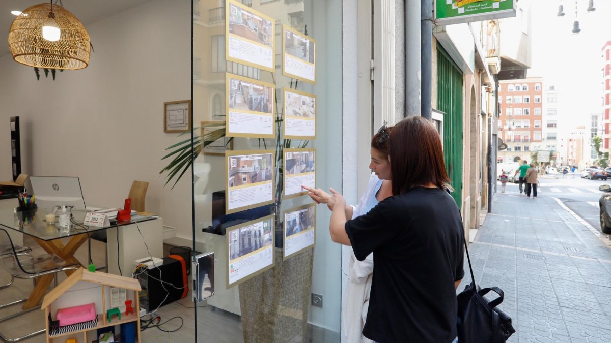 Dos jóvenes comentan las ofertas de una inmobiliaria, en Tarragona.