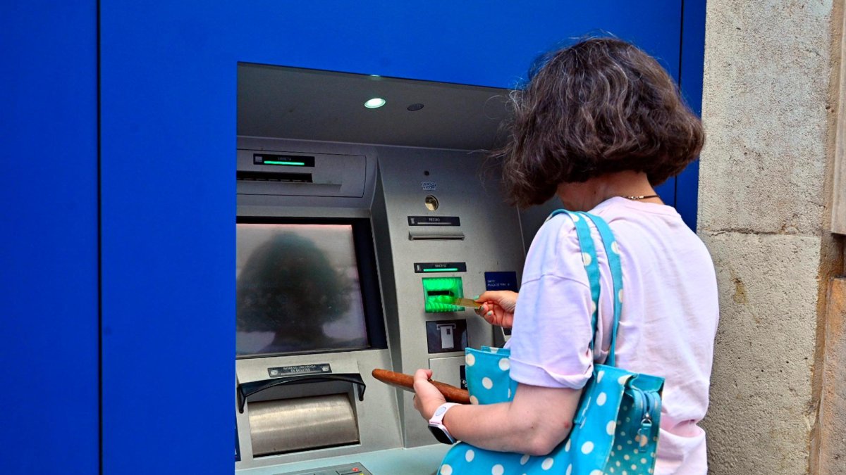 Una dona fent ús d’un caixer automàtic.