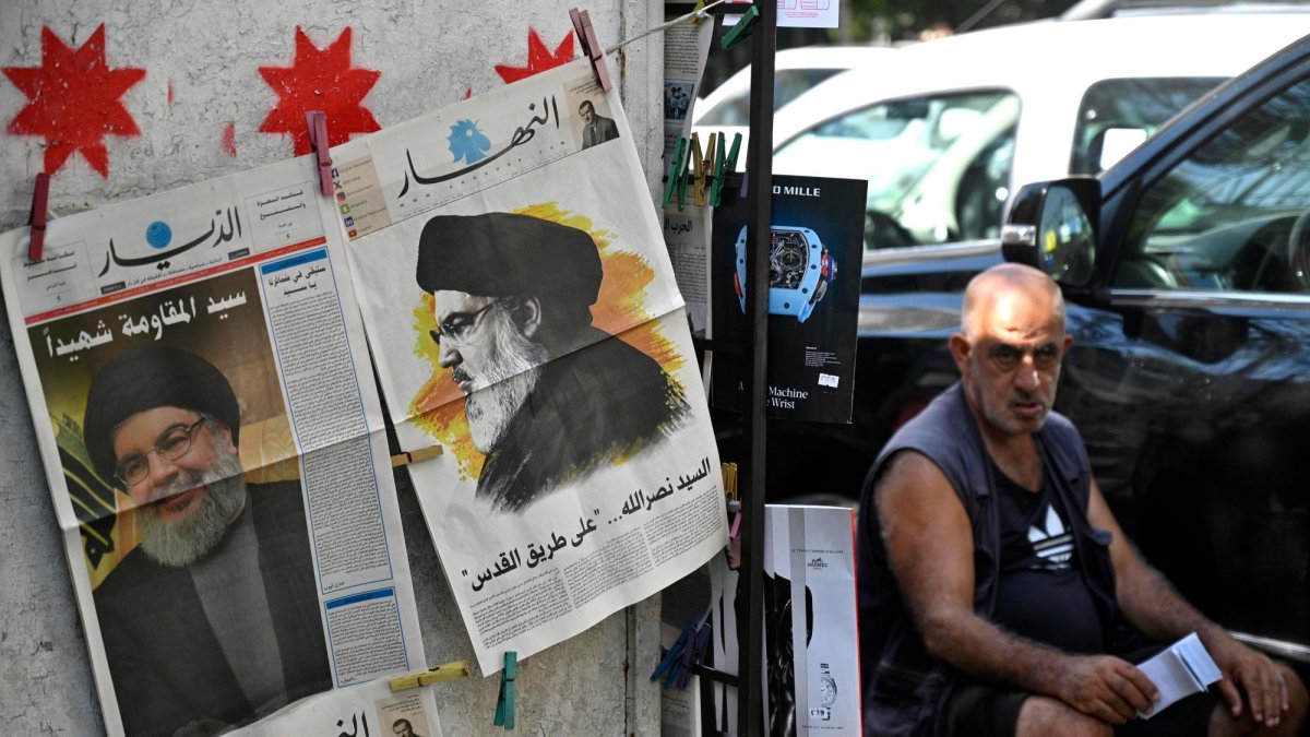 Un hombre se sienta junto a periódicos que informan sobre la muerte del líder de Hezbollah, Hassan Nasrallah, en la calle Hamra en Beirut, Líbano.