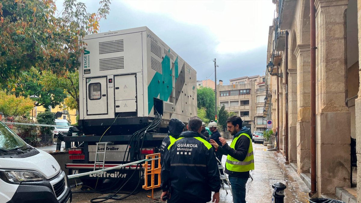 Operarios de Endesa colocando uno de los generadores, con el alcalde de Riudoms, Ricard Gili, y agentes de la Guàrdia Urbana.