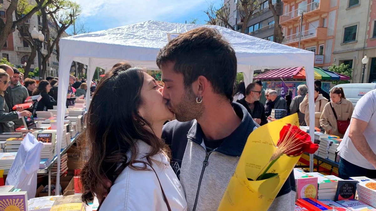 Una pareja de jóvenes frente a una parada de libros.