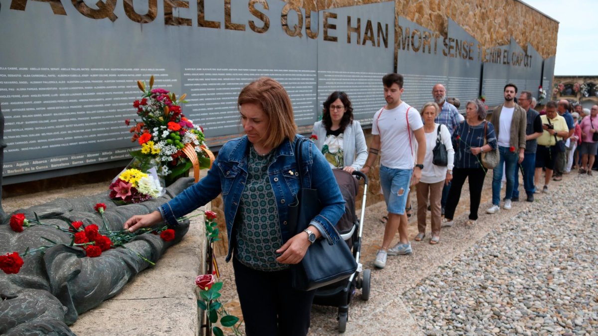 Una dona col·loca una ofrena floral al conjunt escultòric ‘Dignitat’ a una de les fosses comunes del cementiri de Tarragona.