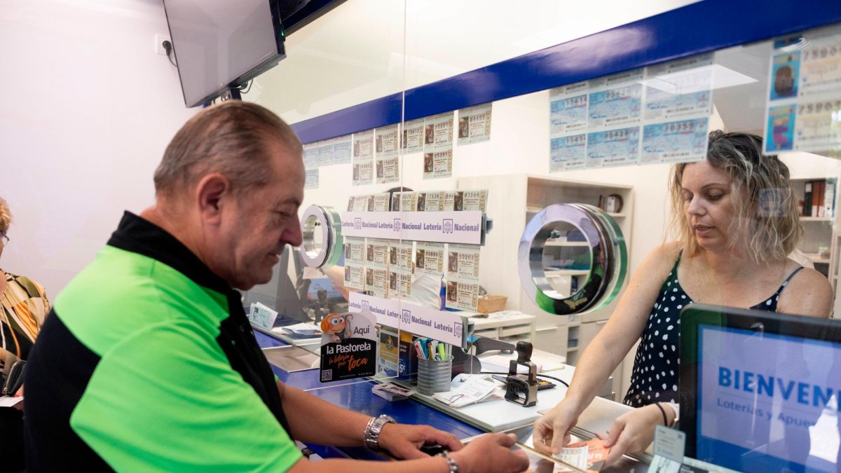 Un hombre compra un décimo de Lotería de Navidad en la ventanilla de la administración La Pastoreta de Reus.