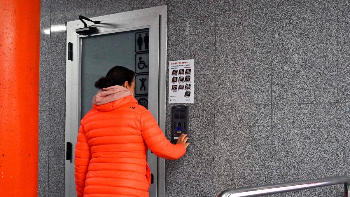 Una mujer pulsando el timbre para acceder a los baños del parking municipal de la Llibertat.