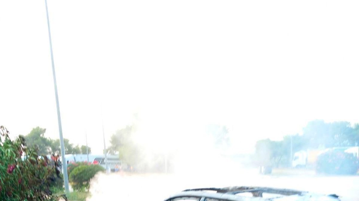 Un bombero apagando las llamas del coche.