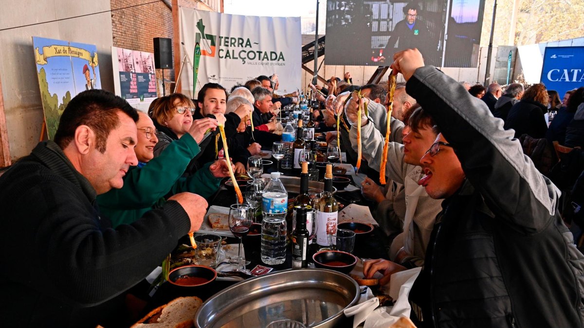 Els convidats de la cooperativa menjant calçots.