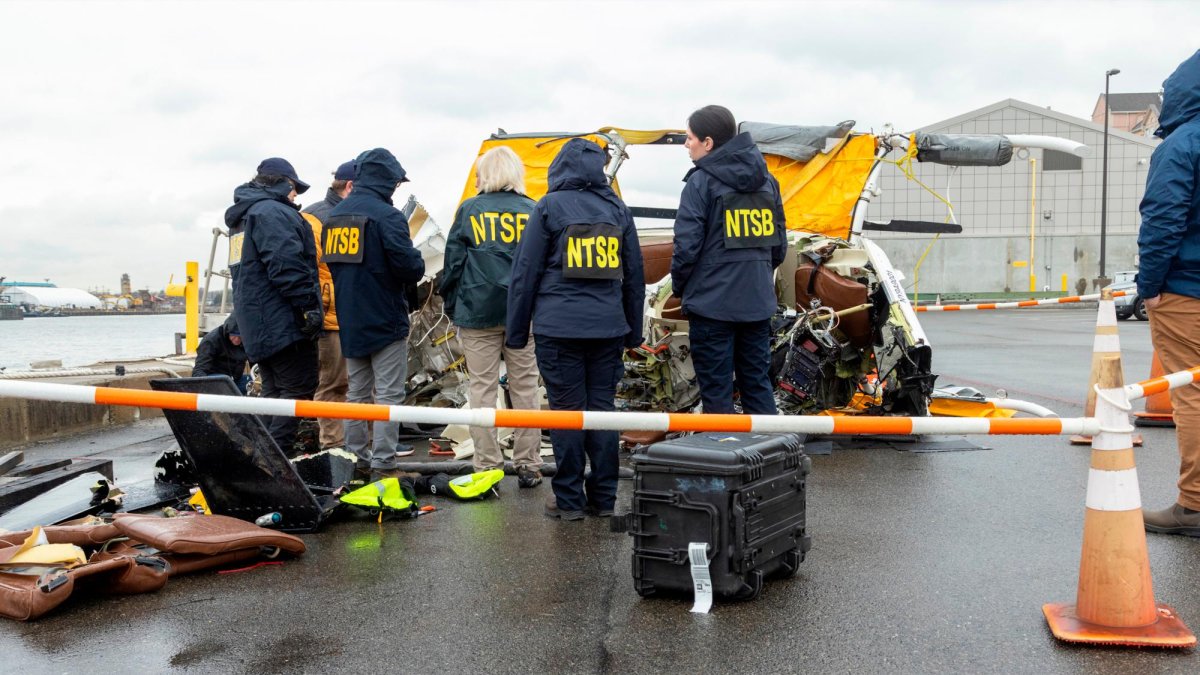 Miembros de la NTSB analizando la cabina del helicóptero recuperada del río.