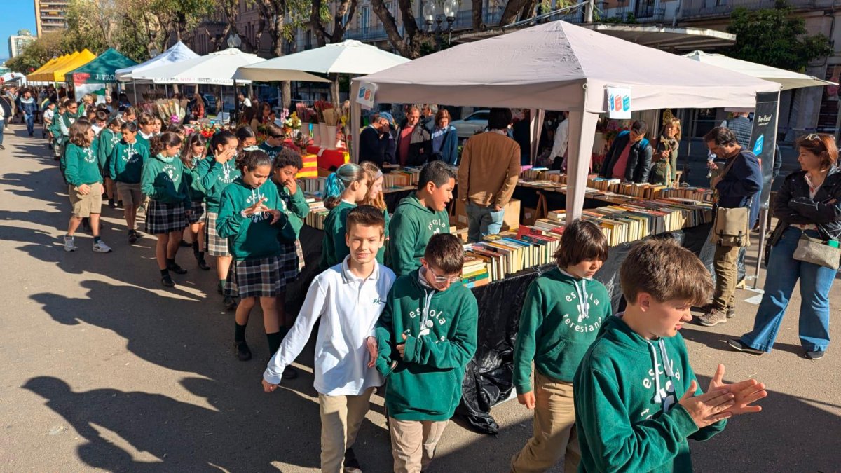 Niños pasean por la Rambla Nova con las paradas de fondo.