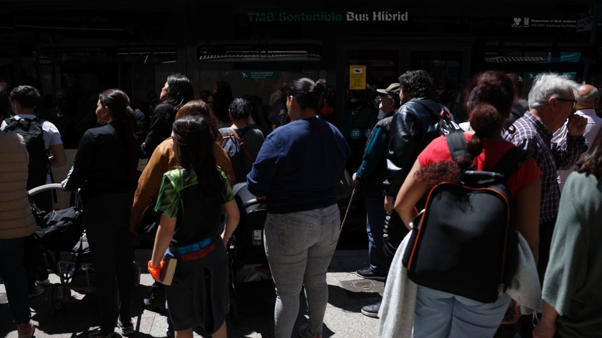 Decenas de personas esperan en una parada de autobús cuyo servicio se ha visto colapsado por la caida del servicio de metro y tranvia, así como de trenes de cercanias por el corte de suministro eléctrico que afecta este lunes a España.