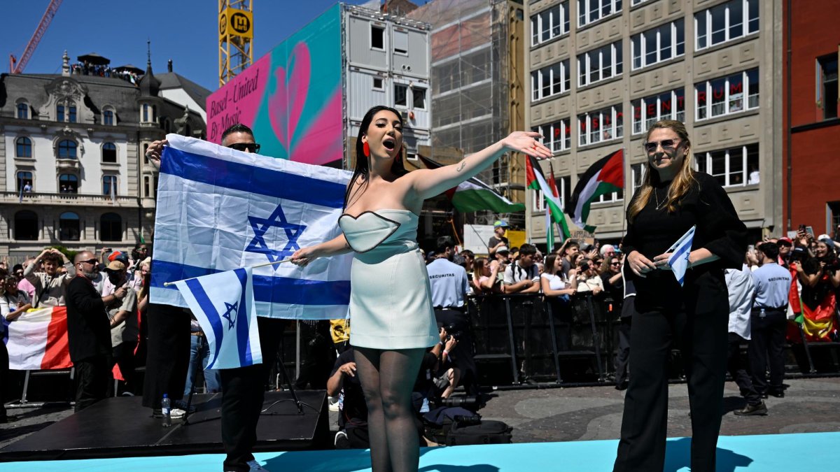 La representante de Israel en Eurovisión, Yuval Raphael, entre banderas israelíes y palestinas, en un acto promocional del festival en Basilea, Suiza.