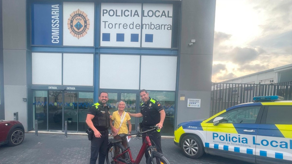 Dos agentes de la Policía Local de Torredembarra y la víctima con la bicicleta recuperada.